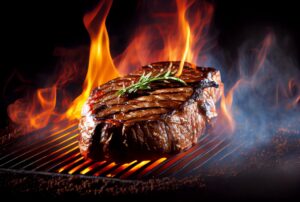 Perfectly charred T-bone steak on a grill with blazing fire flames | Bar-B-Clean